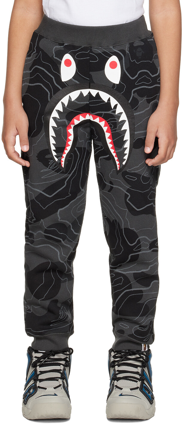 BAPE Kids Серые многослойные спортивные штаны с камуфляжным узором и изображением акулы
BAPE Kids Серые многослойные спортивные штаны с камуфляжным узором и изображением акулы