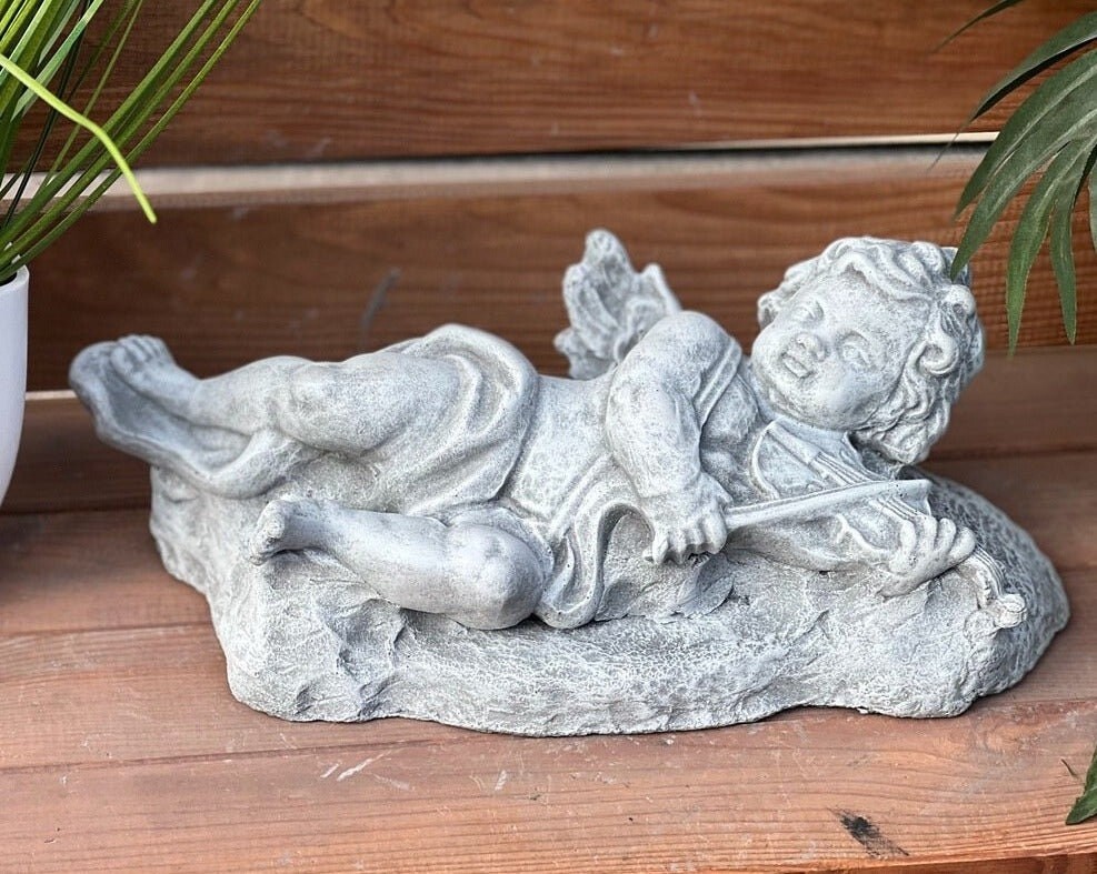 

Каменная фигура ангела, лежащего со скрипкой