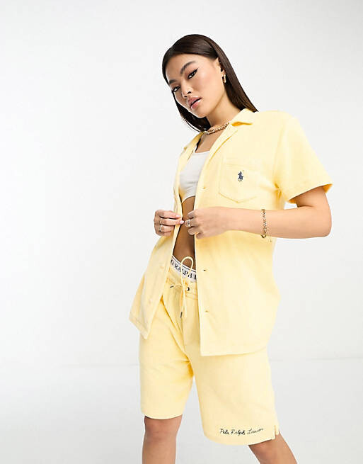 

Желтая махровая рубашка с глубоким воротником и принтом логотипа на спине Polo Ralph Lauren x ASOS.